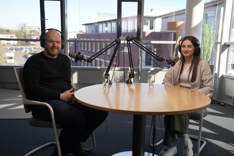 Videopodcast-Host sitzt gegenüber von Podcast Gast. Video Podcast Equipment ist zu sehen