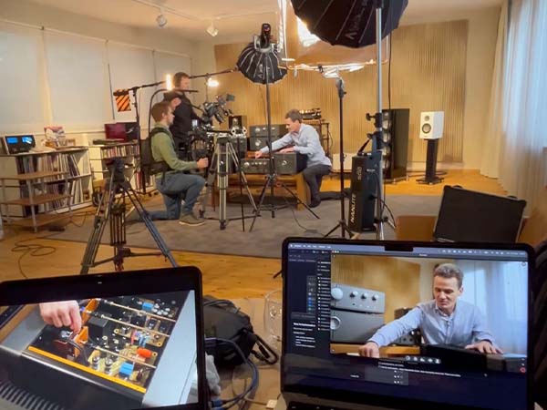 Laptop und kleines Display im Vordergrund mit weißem Teller und Lebensmittelpackung. Deichblick Team filmt Jan Sieveking von Sieveking Sound vor großer HiFi-Anlage im Hintergrund, die er erklärt.