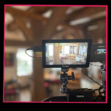 Behind-the-Scenes-Aufnahme eines Videodrehs bei der das Setting über das Kameradisplay sichtbar wird