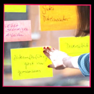 Vorschaubild eines Imagefilms – eine Hand deutet auf bunte Haftnotizen an einem Fenster, Sinnbild für kreative Zusammenarbeit und Planung im Energiebereich